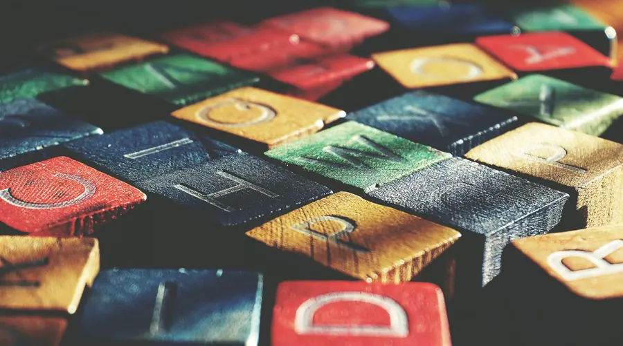 Colourful wooden alphabet blocks in red, blue, green and yellow, tumbled together so that letters like C, H, W, R and D face upward